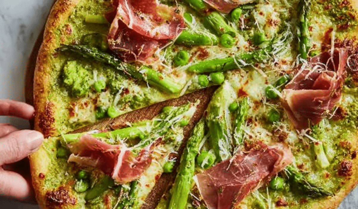 Asparagus Pizza with Green Pea & Prosciutto sliced on a board